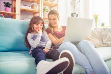 Anne ve kızı dizüstü birlikte, mutlu sevgi dolu bir aile kullanarak