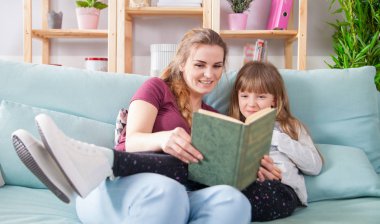 Anne ve kızı koltukta oturan ve birlikte kitap okuma