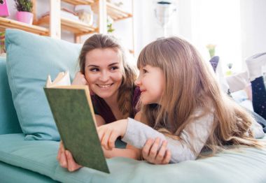 Anne ve kızı koltukta oturan ve birlikte kitap okuma