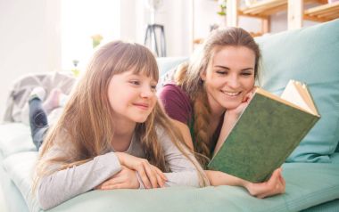 Anne ve kızı koltukta oturan ve birlikte kitap okuma