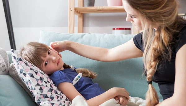 stock image Sick little girl lying in bed mother checking her temperature