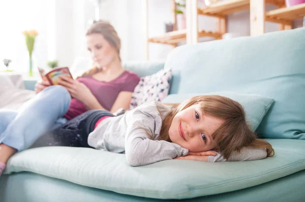 Mãe e filha sentadas no sofá e livro de leitura — Fotografia de Stock