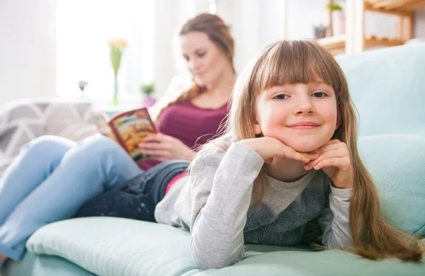 Madre e figlia sedute sul divano e libro di lettura — Foto Stock