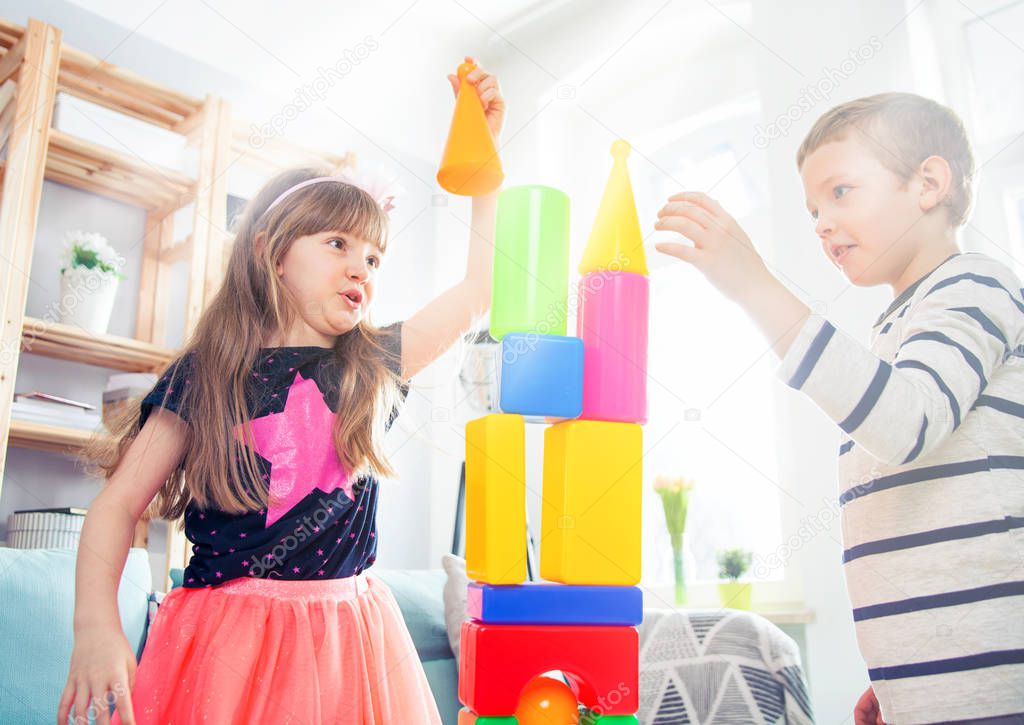 Siblings playing with colorful blocks at home, happy family