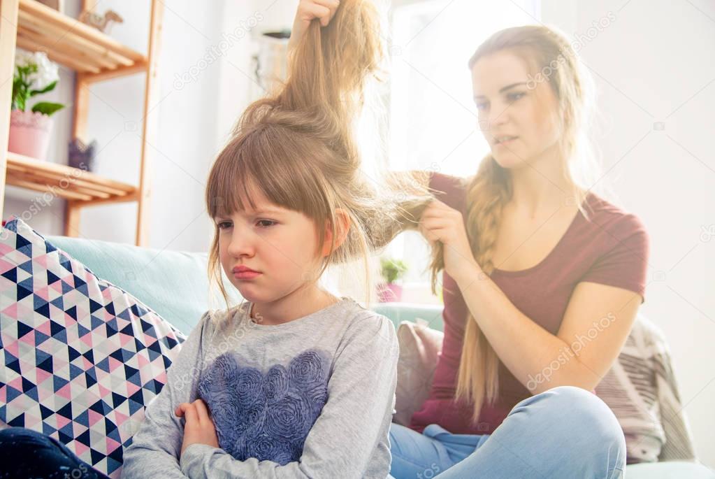 Mother has problem with combing hair of unhappy daughter