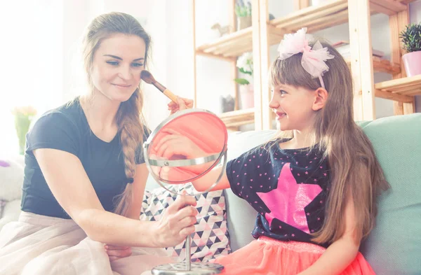 Mother and daughter playing and doing makeup, family at home