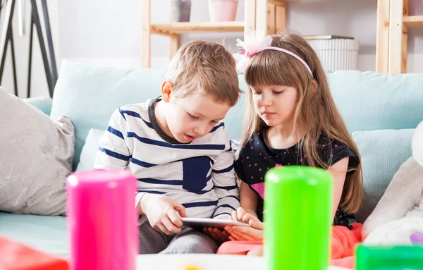 Broers en zussen zittend op de Bank thuis en samenspelen met tablet pc — Stockfoto