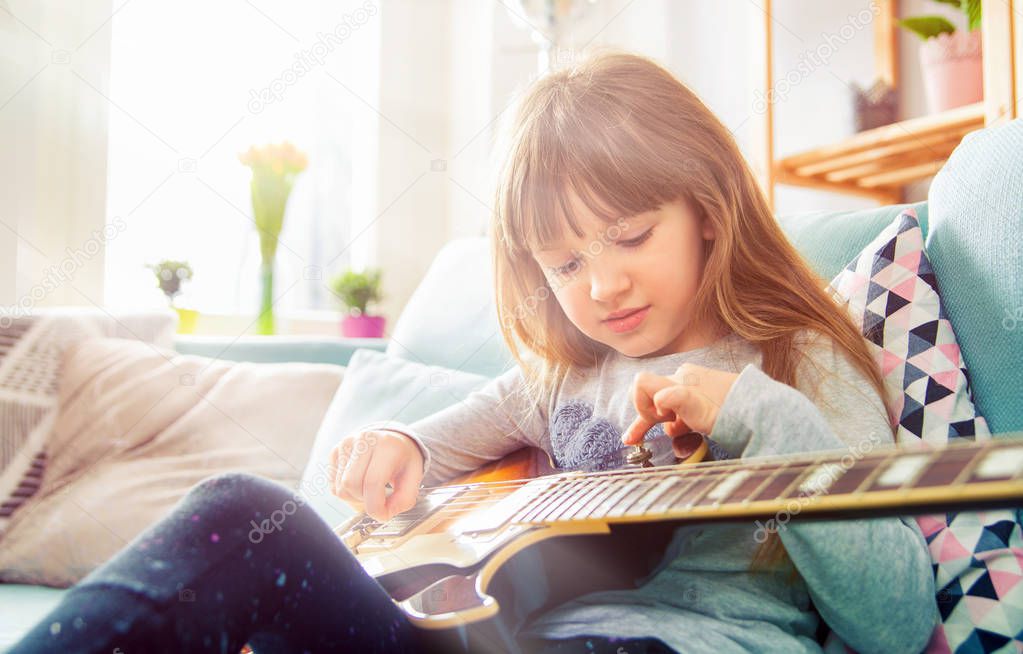 Cute little girl playing guitar at home