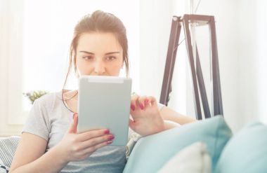 Genç kadın rahat koltukta otururken PC tablet kullanma