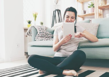 Genç kadın rahat kanepe yakınındaki otururken PC tablet kullanma