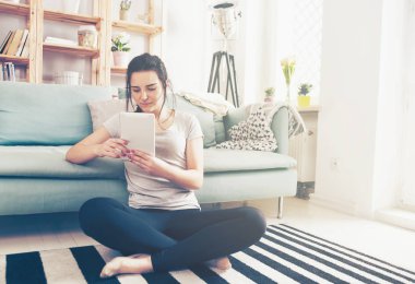 Genç kadın rahat kanepe yakınındaki otururken PC tablet kullanma