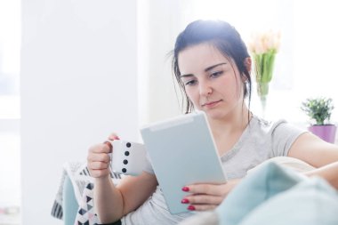 Tablet PC kullanma ve içme kahve evde genç kadın