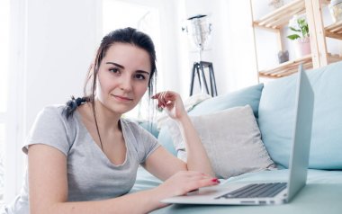 Rahat kanepe, ev yakınındaki otururken dizüstü bilgisayar kullanan genç kadın