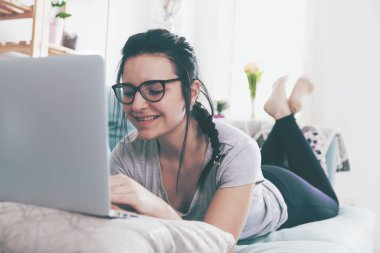 Rahat kanepe, ev yalan sırasında dizüstü bilgisayar kullanan genç kadın