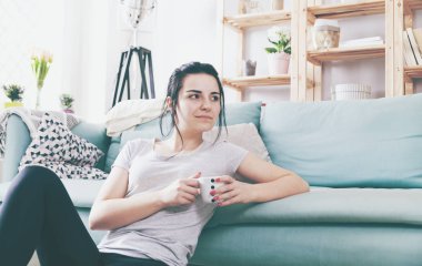 Genç kadın rahat kanepe yakınındaki otururken kahve içme rahat