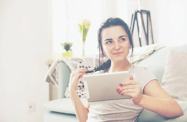 Jonge vrouw met behulp van tablet pc terwijl u zit in de buurt van comfortabele bank — Stockfoto