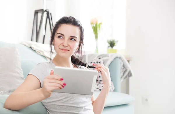 Молодая женщина, используя планшет ПК, сидя рядом с удобным диваном — стоковое фото