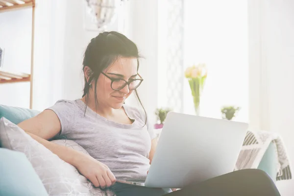 Młoda kobieta za pomocą laptopa siedząc na wygodną sofę, domu — Zdjęcie stockowe