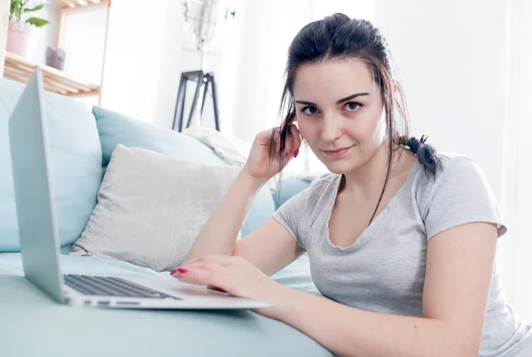 Jovem mulher usando laptop enquanto se senta perto de sofá confortável, casa — Fotografia de Stock