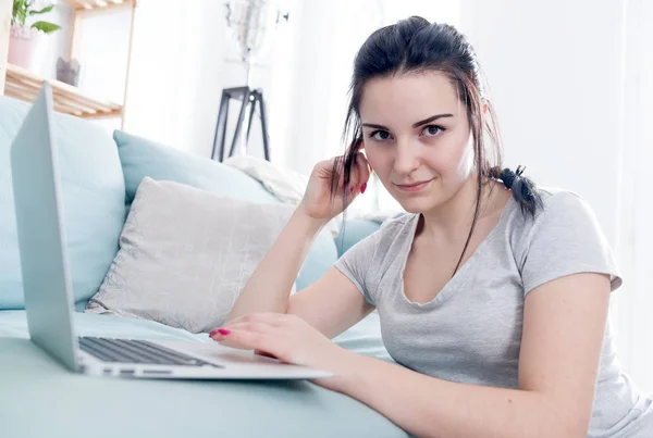 Jonge vrouw met behulp van de laptop terwijl u zit in de buurt van comfortabele bank, thuis — Stockfoto