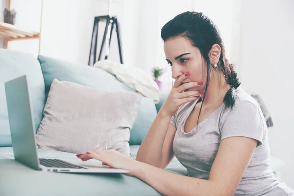 Ung kvinna använder laptop när du sitter nära bekväm soffa, hem — Stockfoto