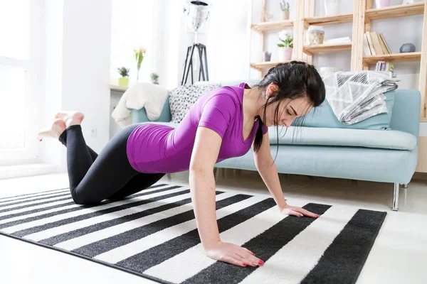 Jeune femme exerçant sur le tapis à l'intérieur de la maison — Photo