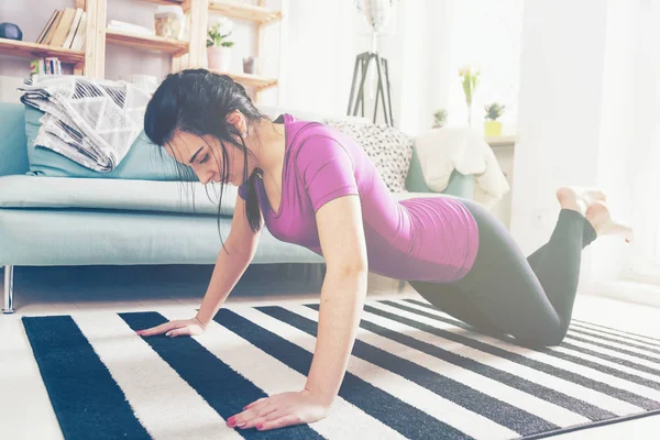 Молода жінка займається на килимі в домашньому інтер'єрі — стокове фото