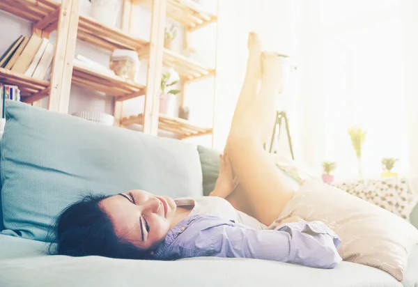 Young relaxed woman with long legs while lying on sofa — Stock Photo, Image