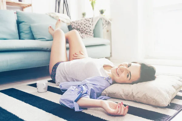 Relaxte vrouw met lange benen liggend op een tapijt thuis — Stockfoto