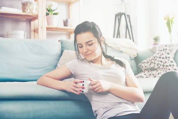 Giovane donna rilassata bere caffè mentre seduto vicino comodo divano — Foto Stock