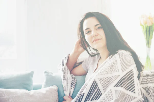 Joven mujer feliz relajado mientras está sentado en un cómodo sofá, en casa —  Fotos de Stock