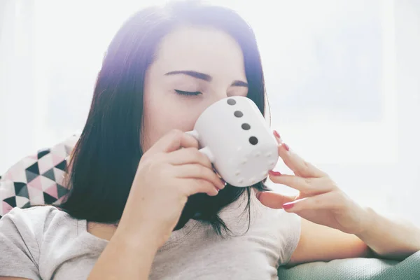 Genç mutlu kadın kanepede otururken kahve içme rahat — Stok fotoğraf