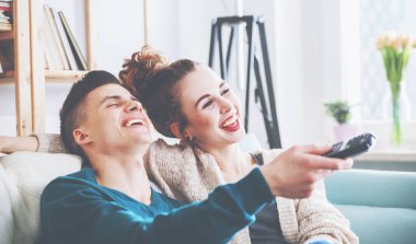 Sevgi dolu çift evde kanepe üzerinde tv izliyor ve gülüyor