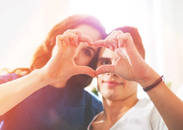 Älskande par hemma att göra hjärta form med händerna — Stockfoto