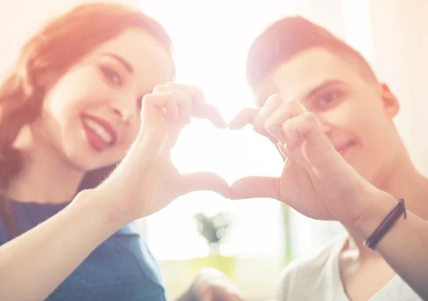 Loving couple at home making heart shape with hands — Stock Photo, Image