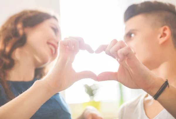 Couple aimant à la maison faisant forme de coeur avec les mains — Photo