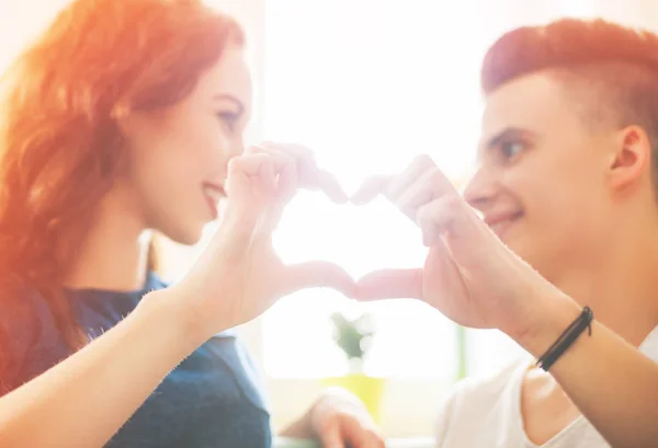 Loving couple at home making heart shape with hands — Stock Photo, Image