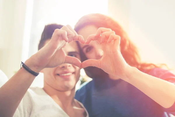 Coppia amorevole a casa facendo forma di cuore con le mani — Foto Stock