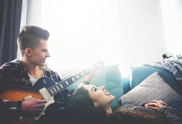 Casal tocando guitarra e cantando no sofá em casa — Fotografia de Stock