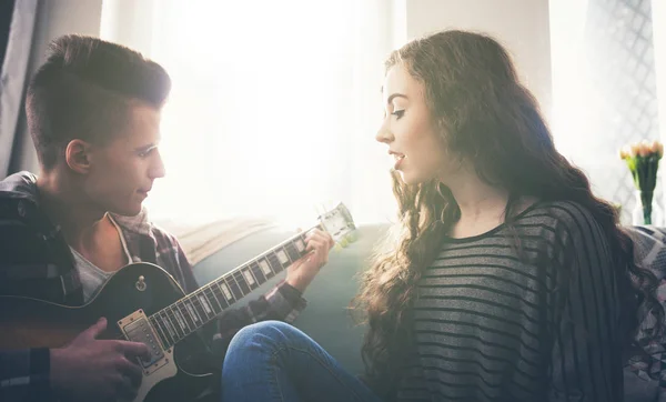 Casal tocando guitarra e cantando no sofá em casa — Fotografia de Stock