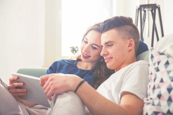 Couple sur canapé à la maison en utilisant une tablette numérique et souriant — Photo