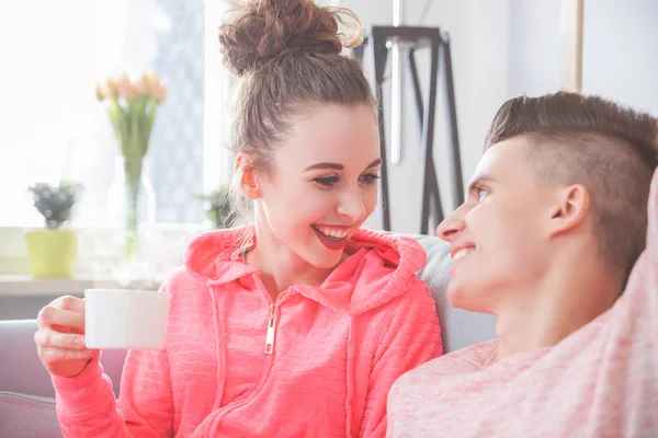 Casal em roupas rosa relaxante e falando no sofá em casa — Fotografia de Stock