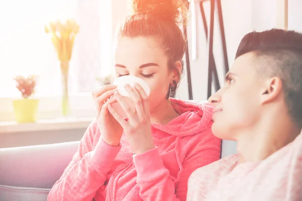 Młoda para relaksujący i picia porannej kawy na kanapie w domu — Zdjęcie stockowe