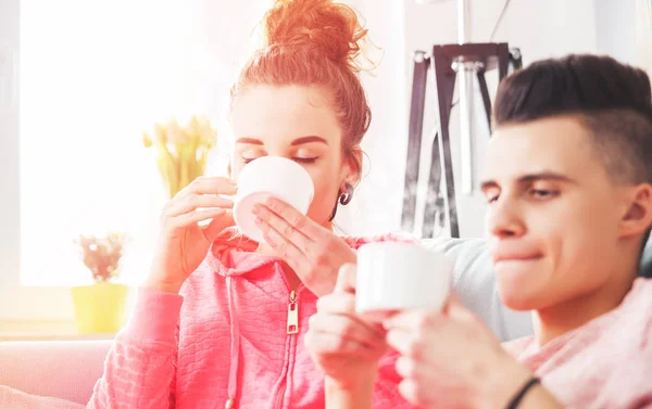 Jeune couple se détendre et boire le café du matin sur le canapé à la maison — Photo