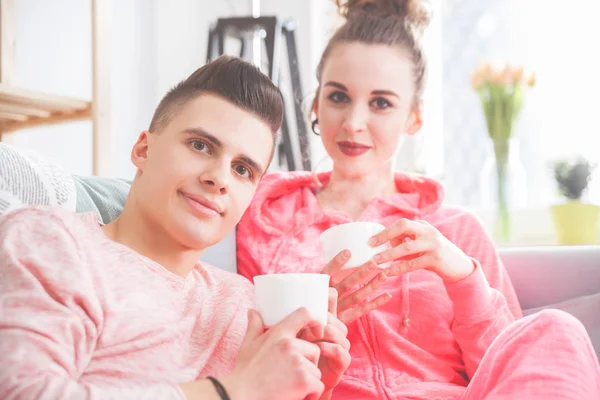 Młoda para relaksujący i picia porannej kawy na kanapie w domu — Zdjęcie stockowe