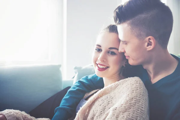 Loving young couple hugging and lying on sofa at home — Stock Photo, Image