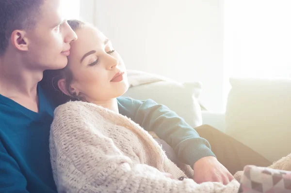 Loving young couple hugging and lying on sofa at home — Stock Photo, Image