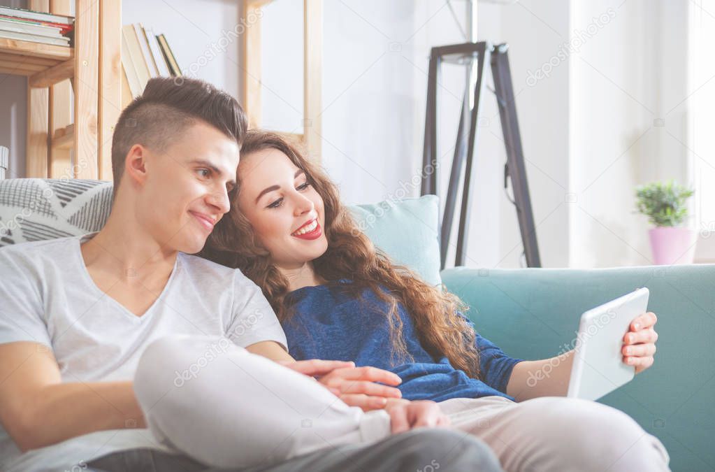 Young couple on sofa at home using pc tablet