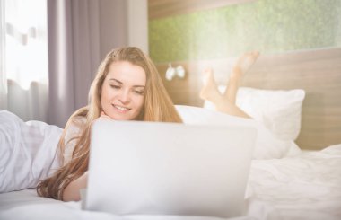 Modern daire dizüstü kullanarak uyku modundan çıkarma sonra yatakta güzel kadın