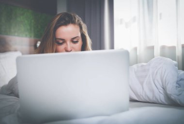 Modern daire dizüstü kullanarak uyku modundan çıkarma sonra yatakta güzel kadın